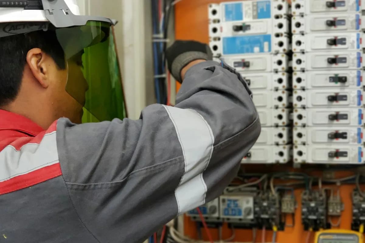 Técnico inspeccionando las conexiones de un tablero de control